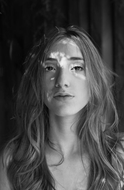 Stylish monochromatic portrait of a young woman with long hair illuminated by soft light.