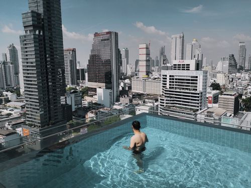 Free Man in rooftop pool with stunning view of Bangkok skyscrapers, Thailand. Stock Photo