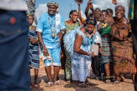 在晴朗的天空下，人们穿着传统服装，欢乐地跳舞庆祝户外聚会