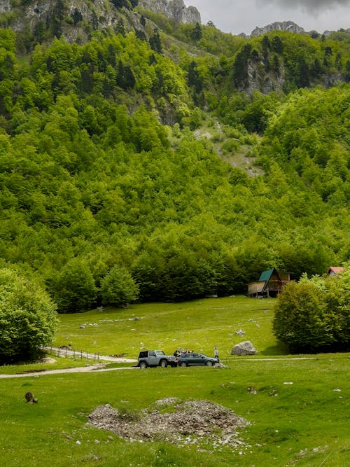 A car is parked in front of a green mountain