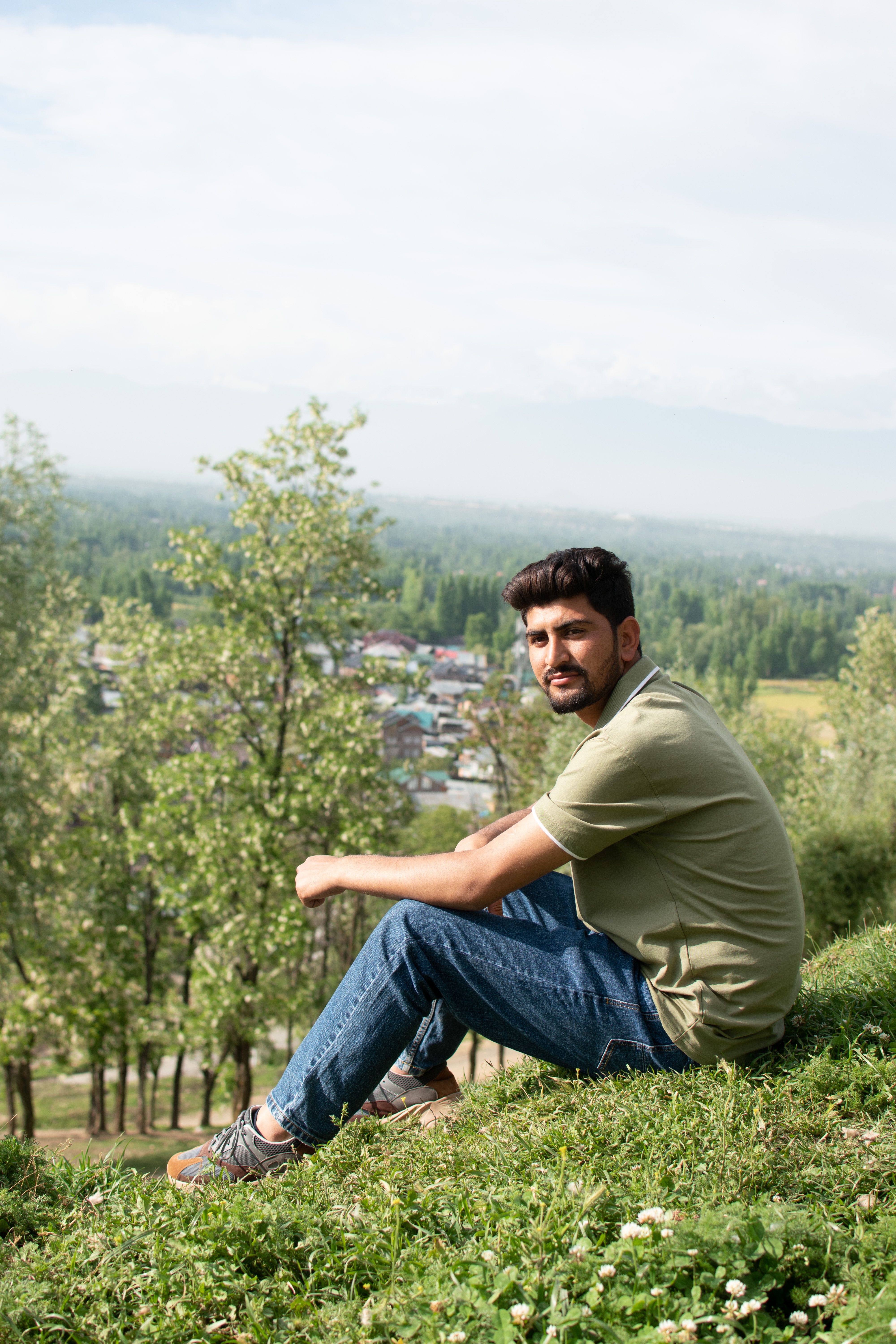 Man sitting on a hill in Srinagar, enjoying a scenic view of the countryside.
