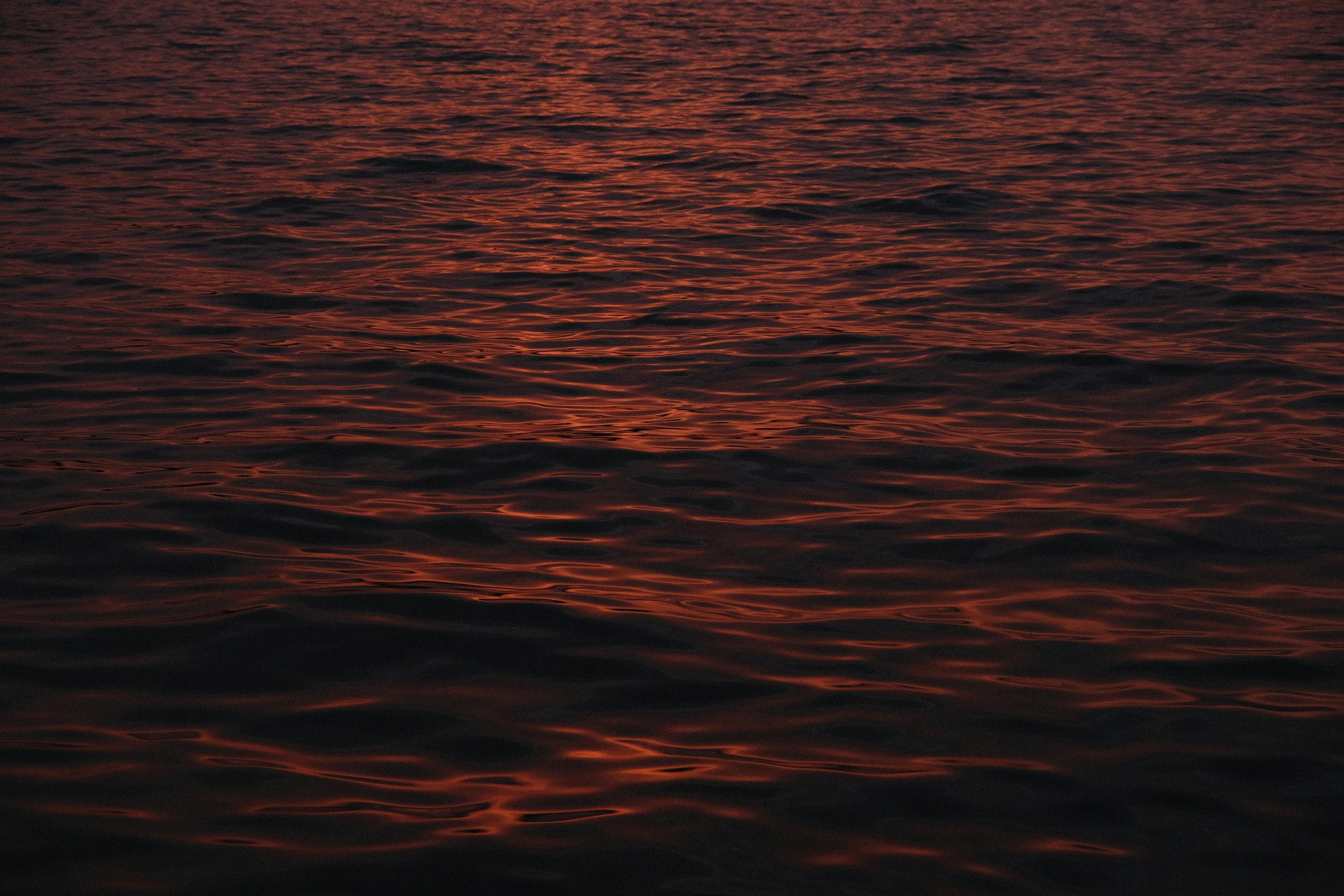 Calm ocean waves illuminated by the warm glow of the sunset, creating a peaceful scene.
