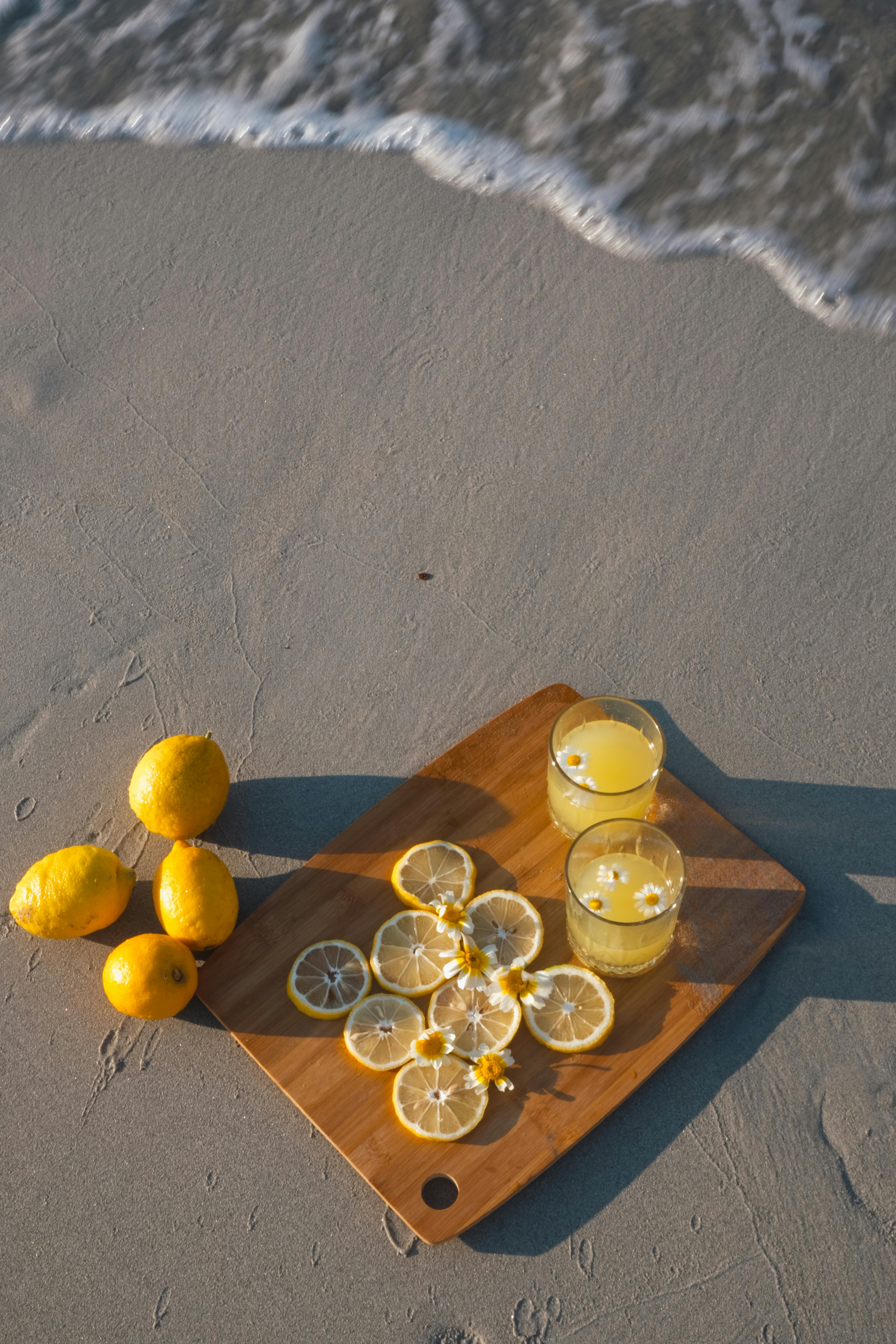 Top view of lemonade and lemons on a wooden board by the sea waves.