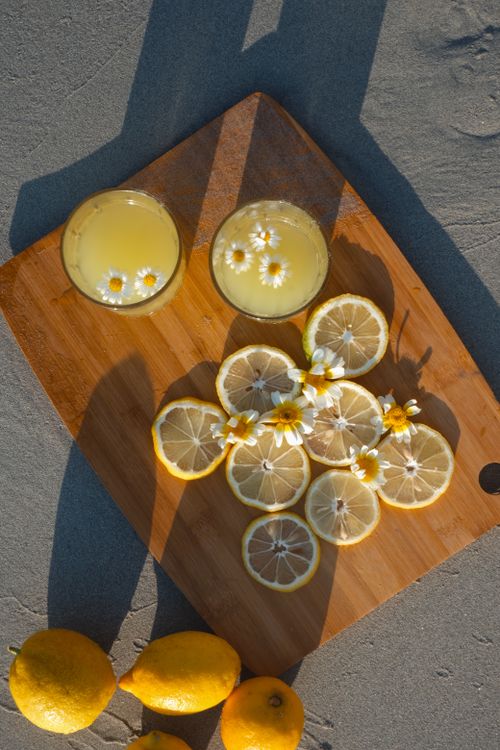 Free Top view of glasses with lemonade, lemon slices, and flowers on a wooden tray. Stock Photo
