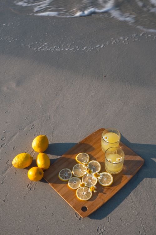 Free Fresh lemonade and sliced lemons on a beach, capturing the essence of summer. Stock Photo
