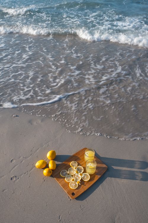 Free Lemonade and lemons on a tray by the beach, capturing summer vibes. Stock Photo
