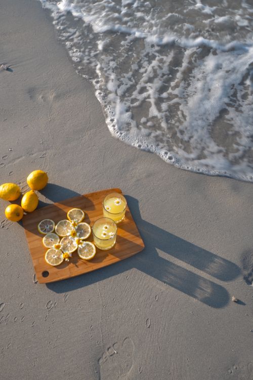 Free Two glasses of fresh lemonade with lemons on a sandy beach during summer. Stock Photo