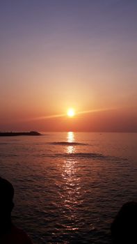 Vibrant sunset over Kanniyakumari's serene ocean view, capturing the sun's reflection on tranquil waters.