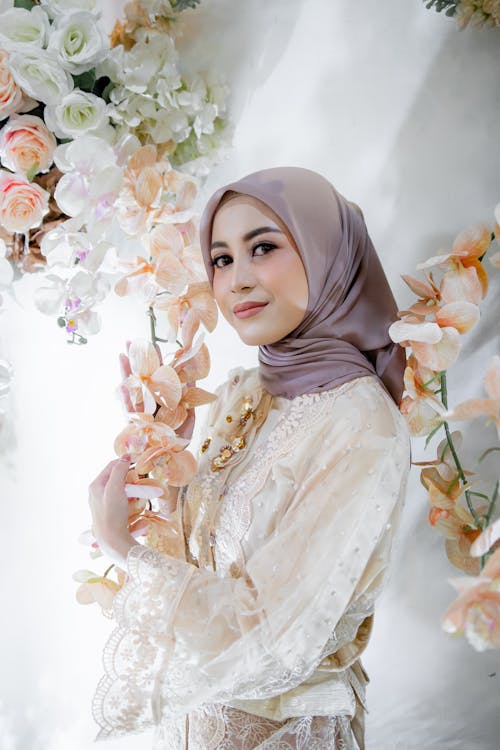 A woman in a white dress and headscarf posing for a photo