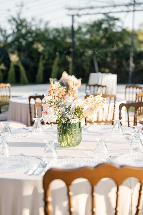 A table set for a wedding reception with white tablecloths and flowers