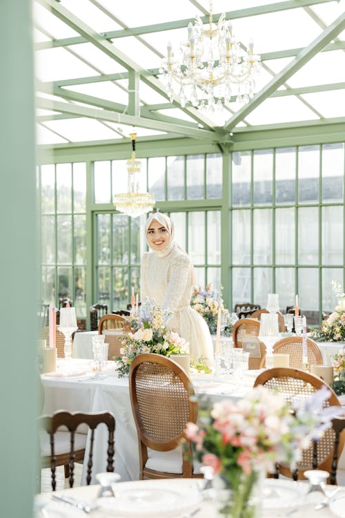 A bride and groom are standing in the middle of a large greenhouse