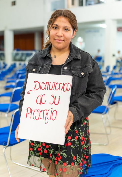 Free Young woman standing in Ciudad de México auditorium holding an inspiring message sign. Stock Photo