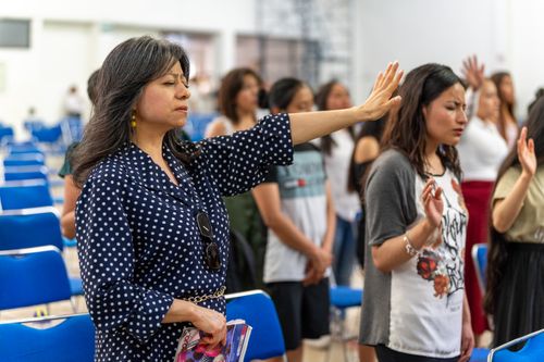 Free Devout gathering in Ciudad de México, women praying with raised arms in church. Stock Photo