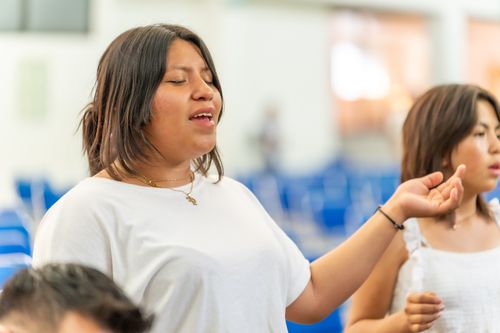 Free Young woman in Ciudad de México praying with eyes closed during a religious service. Stock Photo