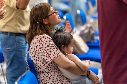 Free Mother holding child in a church setting during worship in Mexico City, reflecting spirituality and togetherness. Stock Photo