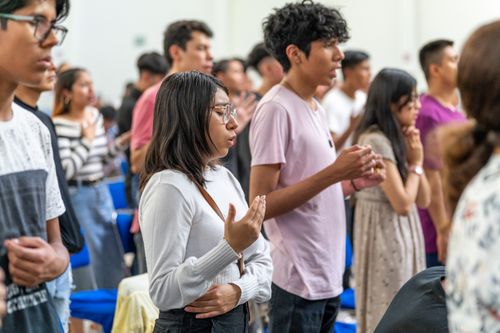 Free Young adults praying in church, Ciudad de México. Capturing spirituality and unity in worship. Stock Photo