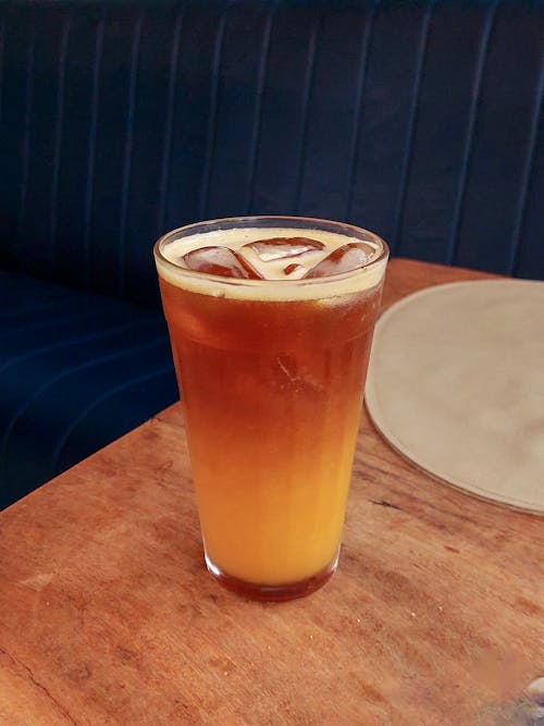 A glass of iced tea sitting on top of a wooden table