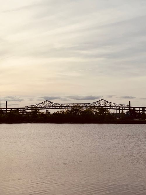 Free A picturesque view of a bridge silhouette at sunset over the calm ocean waters. Stock Photo