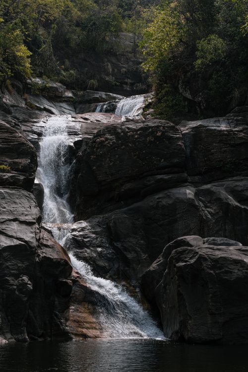 Free A tranquil waterfall cascading over rocks in the lush forests of Kallar, Kerala, India. Stock Photo