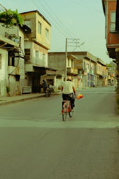 A man rides a bicycle down a quiet street in the historic town of Tarsus, Türkiye.