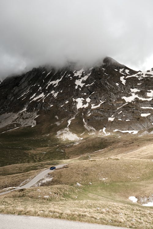 A car is parked on the side of a mountain road