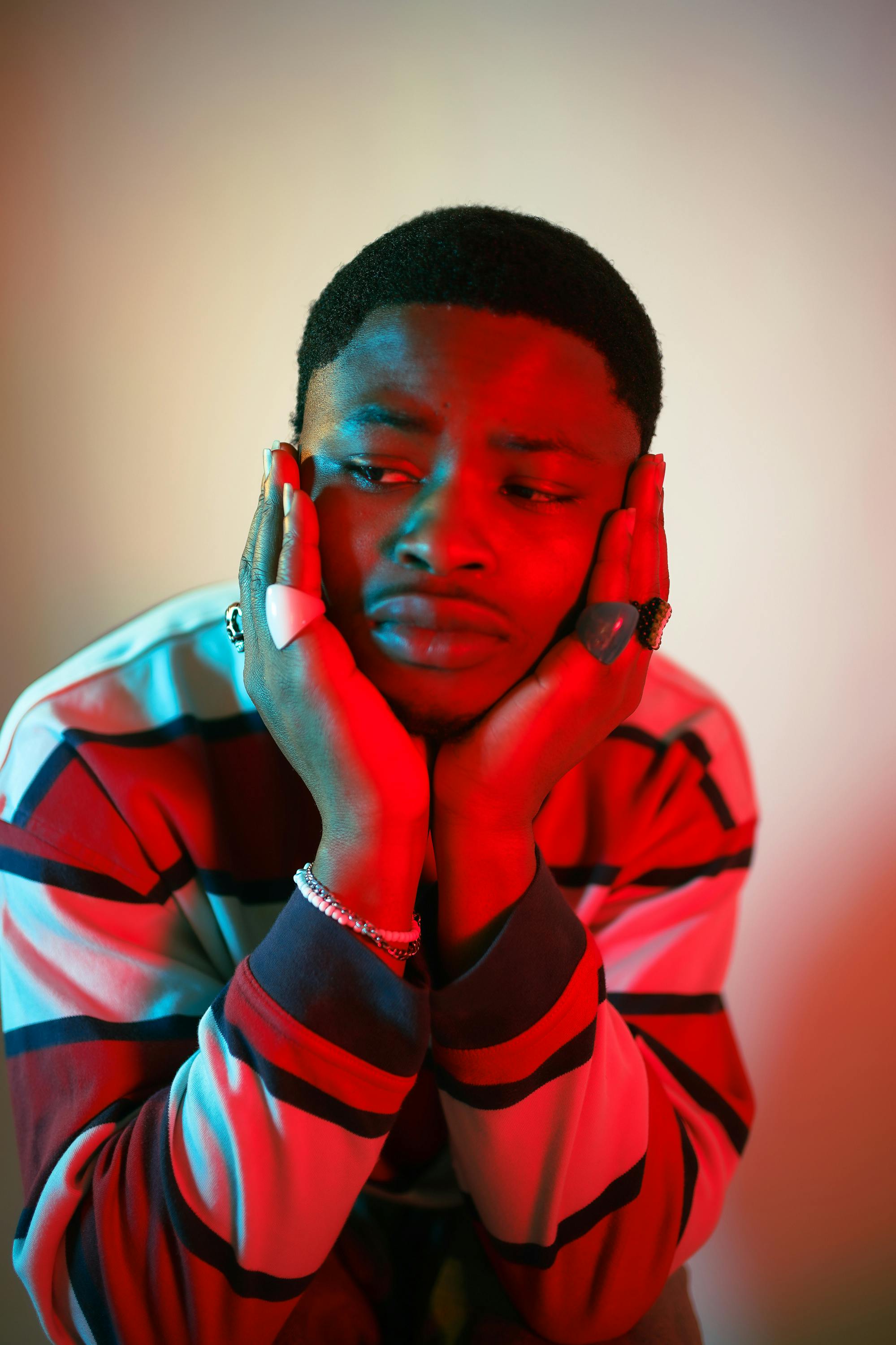 A fashionable portrait of a man with red and blue lighting in a studio setting, expressing contemplation.