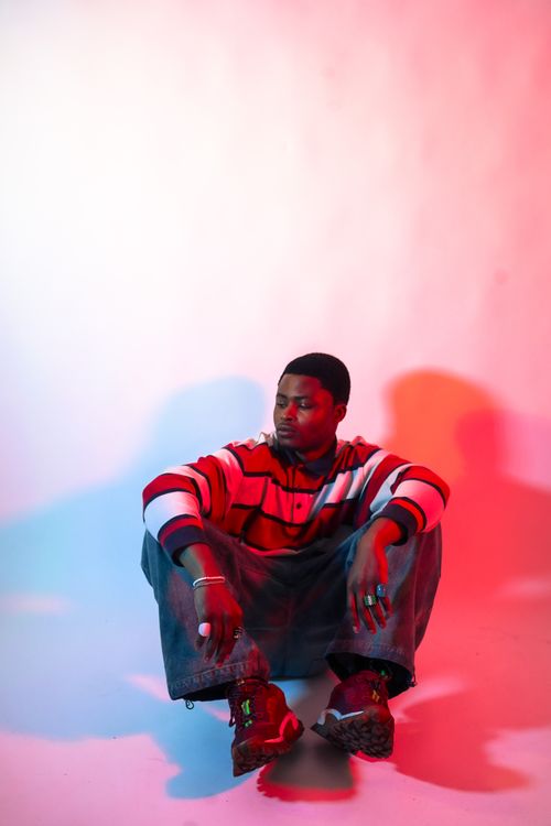 Free Stylish male model posing in striped sweater with dynamic lighting in studio. Stock Photo