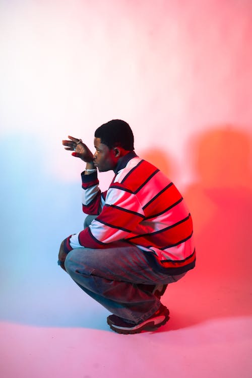 A man crouching down in front of a red and blue wall