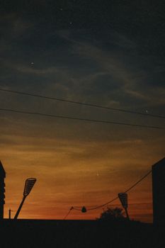 Silhouetted city skyline against a colorful evening sky with visible stars.