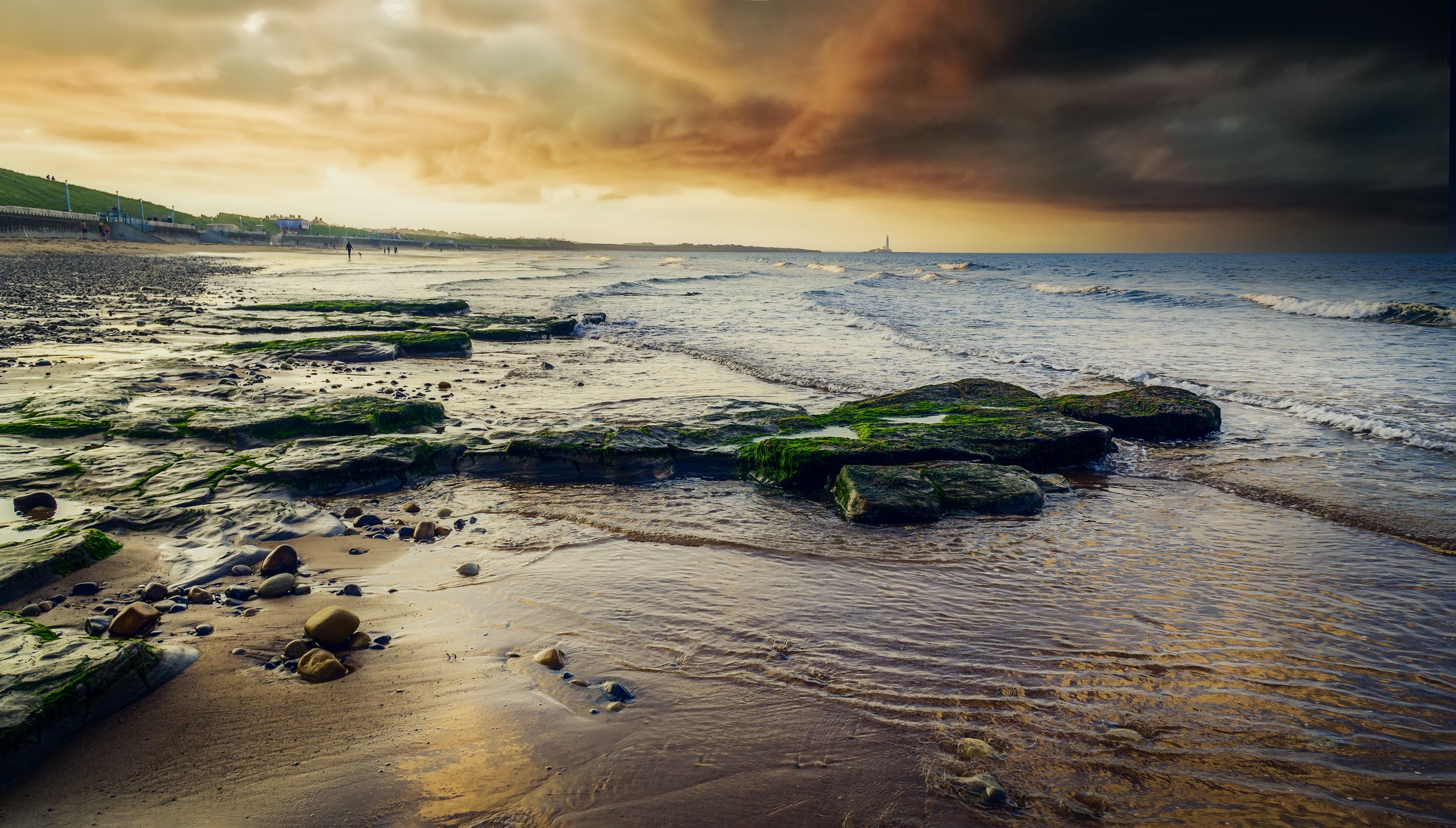 A beach with rocks and water at sunset · Free Stock Photo