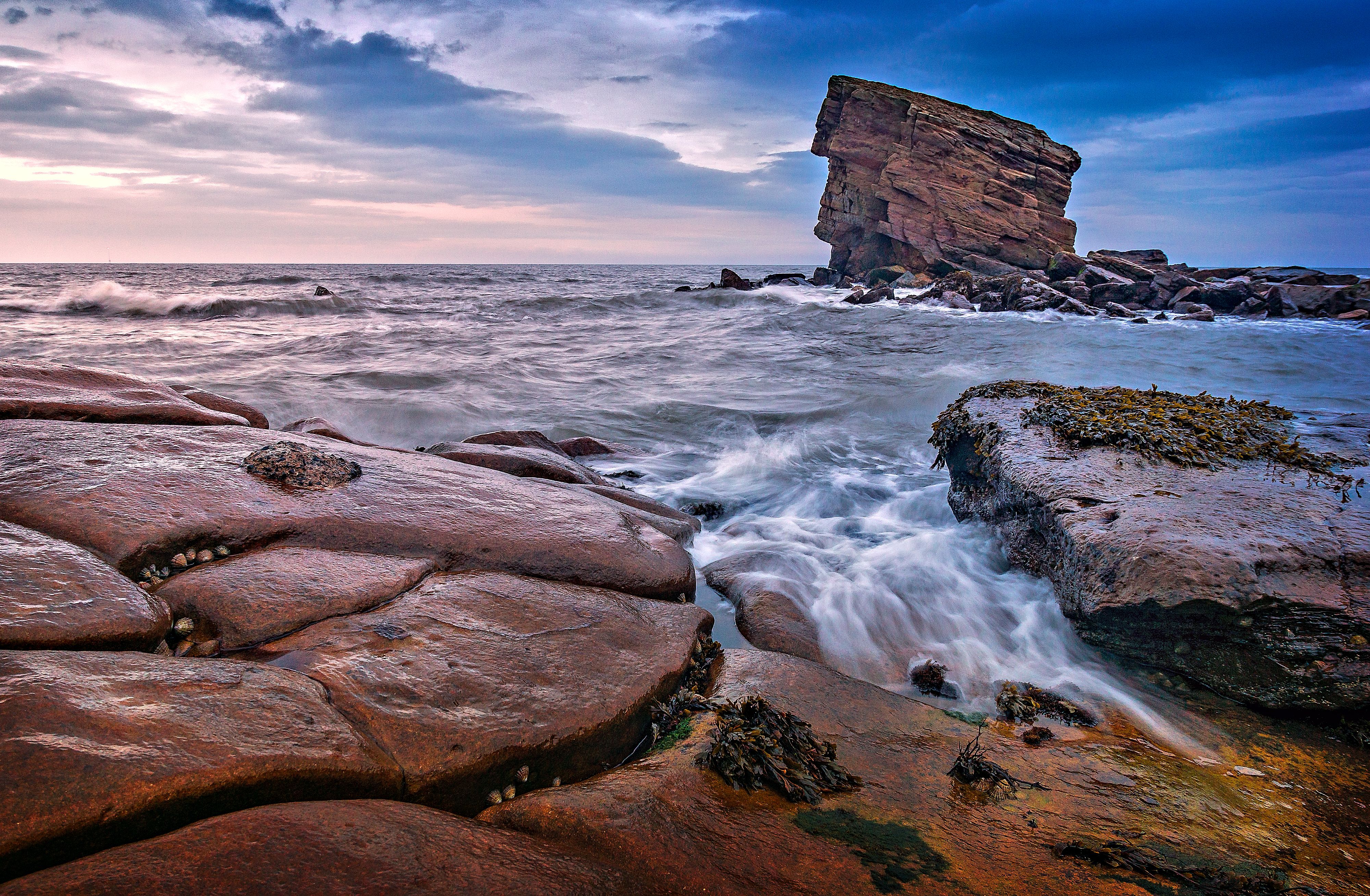Stunning view of the iconic sea stack in Colywell Bay, Northumberland, under a cloudy sky.