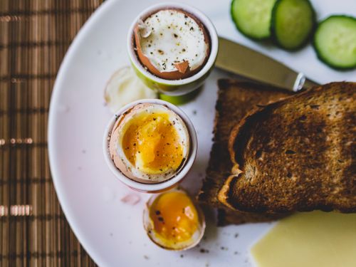 Free Top view of a breakfast plate featuring soft boiled eggs and toast, ideal for a nutritious meal. Stock Photo