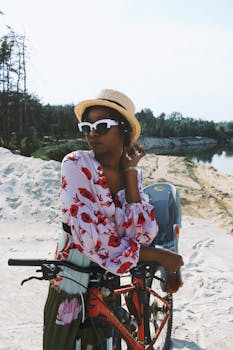 一位戴着帽子、骑着自行车的时尚女士，正在户外享受明媚的阳光