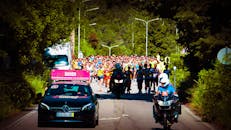 前方拍摄到一大群参加户外马拉松的跑步者，视野中可以看到支持车辆