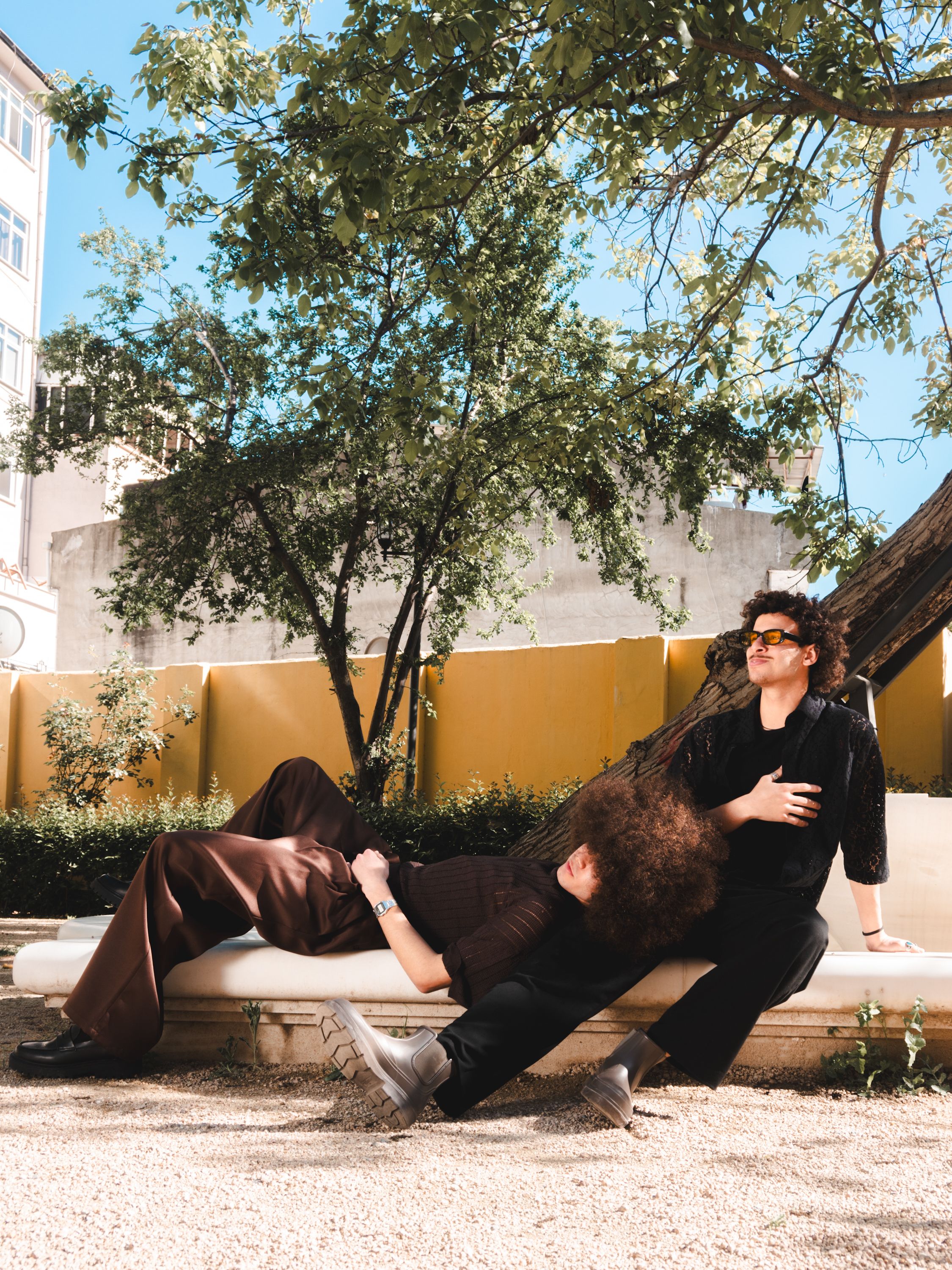 Two people sitting on a bench in front of a building · Free Stock Photo