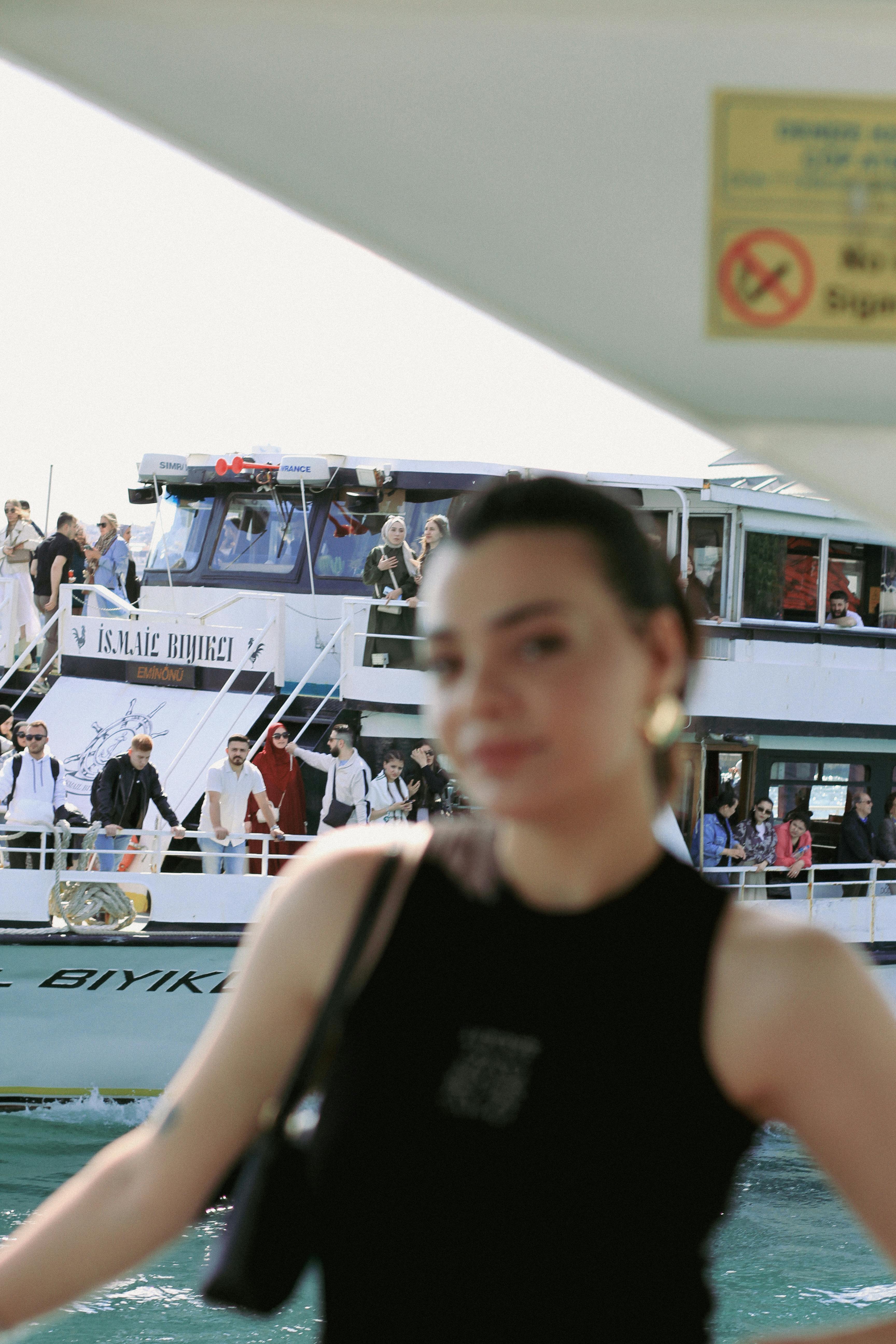 Blurred image of a woman posing with a passenger ferry in the background, capturing a dynamic waterfront scene.