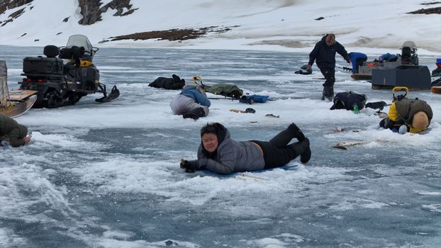 Group of adults ice fishing on a frozen lake in winter.