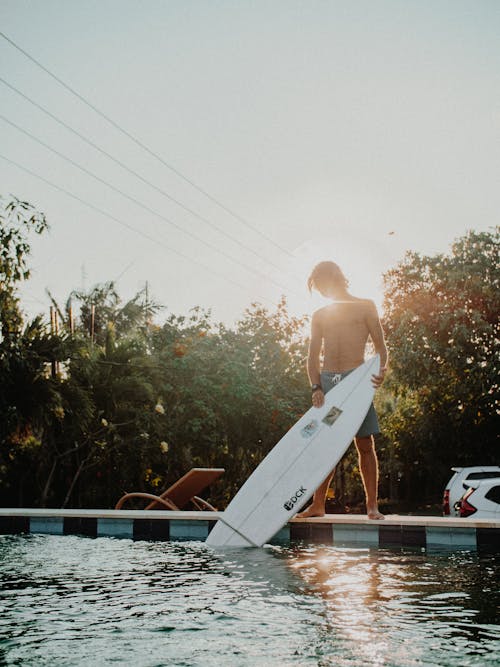 Man Standing by Concrete Holding Surfboard