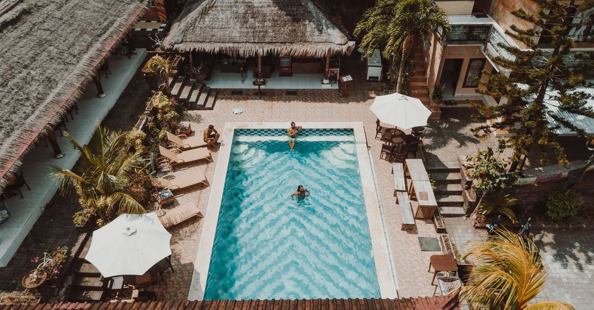 Aerial view of a luxury resort pool surrounded by villas and palm trees.