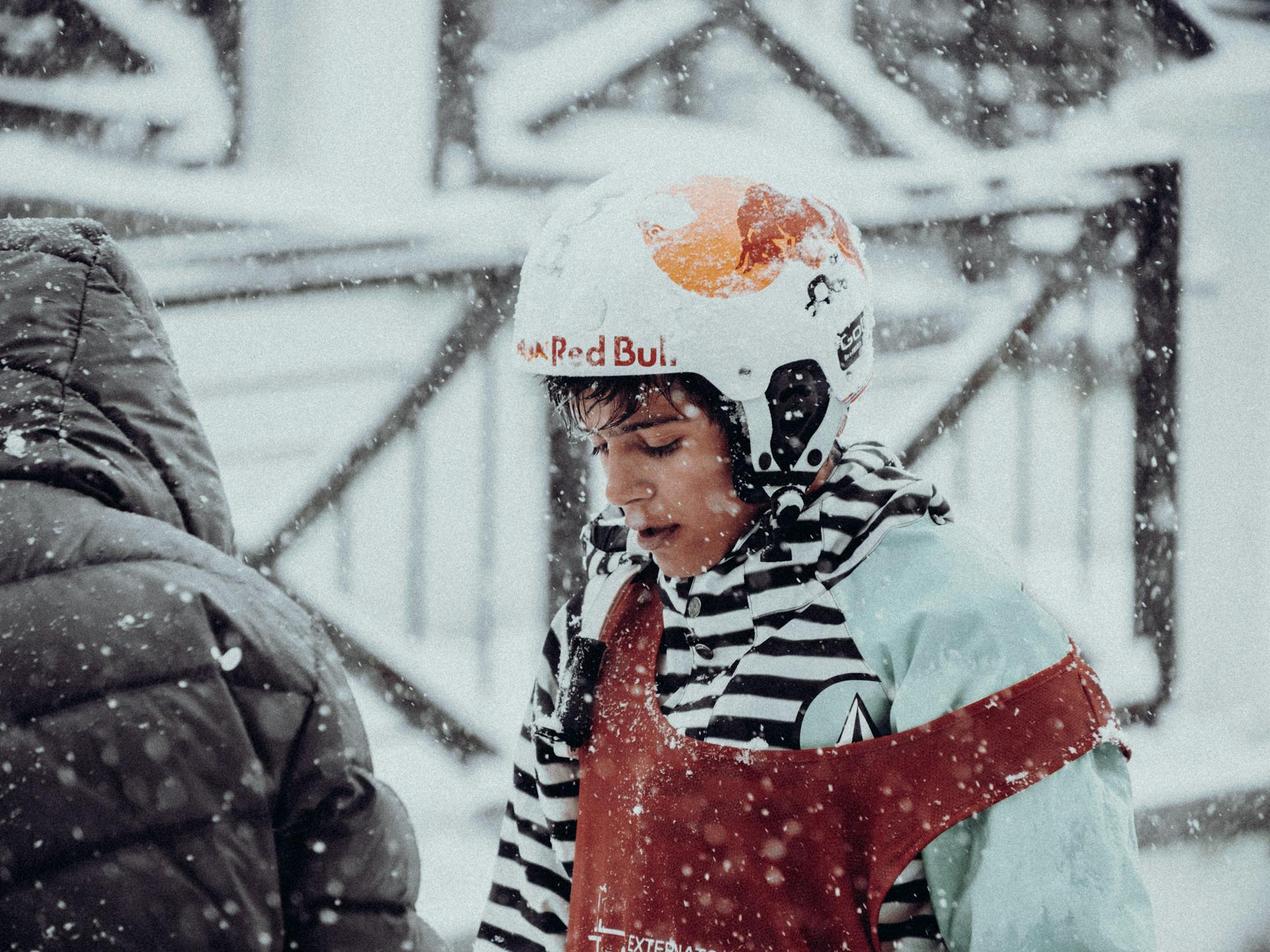 Teenager in protective gear during a winter snowfall, showcasing safety and winter sports.