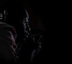 这是一幅在弱光下拍摄的男子特写肖像，引人注目，展现了深刻的沉思