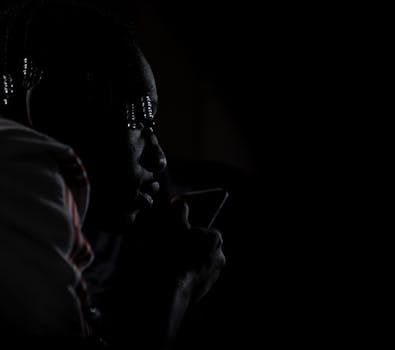 这是一幅在弱光下拍摄的男子特写肖像，引人注目，展现了深刻的沉思