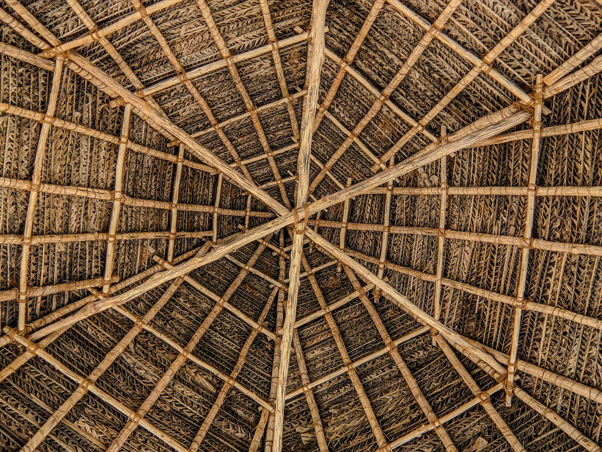 Close-up view of a traditional thatched roof with bamboo beams creating intricate patterns, Puducherry, India.