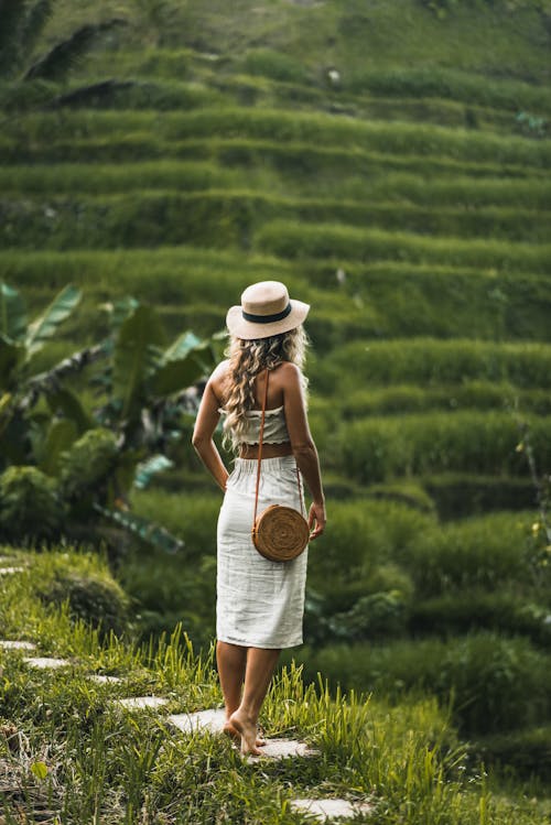 Woman in White Hat and White Dress Standing on Top of Mountian