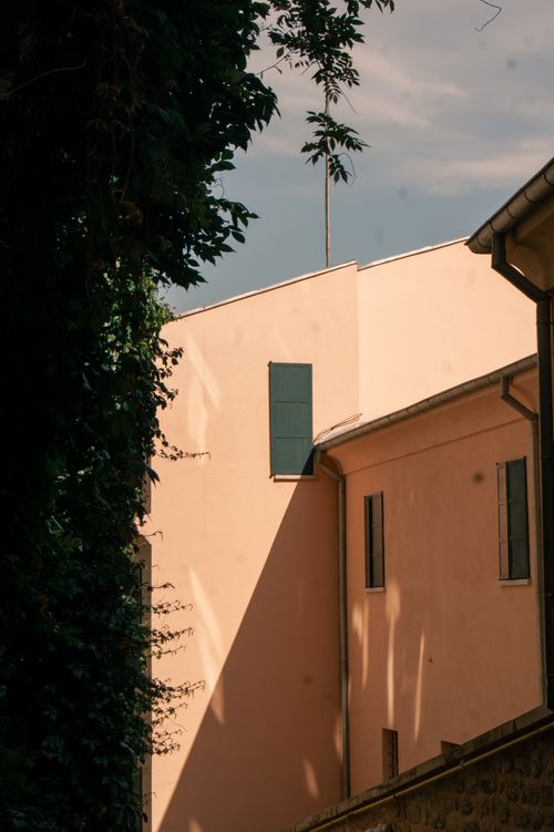 Free Sun-drenched exterior of a modern urban building with shadows and greenery. Stock Photo