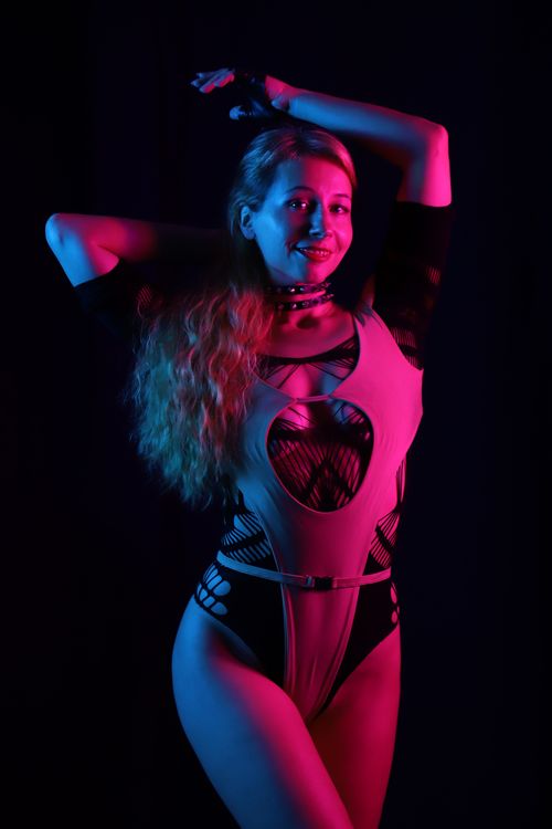 Free Fashion model posing in a bodysuit with dramatic red and blue studio lighting. Stock Photo
