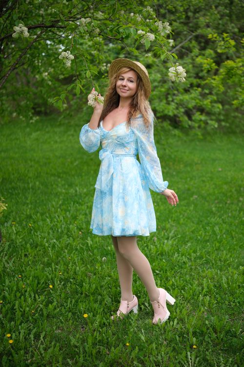 Free Woman in a blue dress and hat enjoying a sunny day in a park. Stock Photo