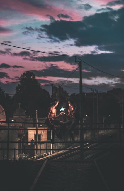 Two people on a rooftop in Saronno, Italy, captured during a moody dusk with vibrant, dramatic skies.
