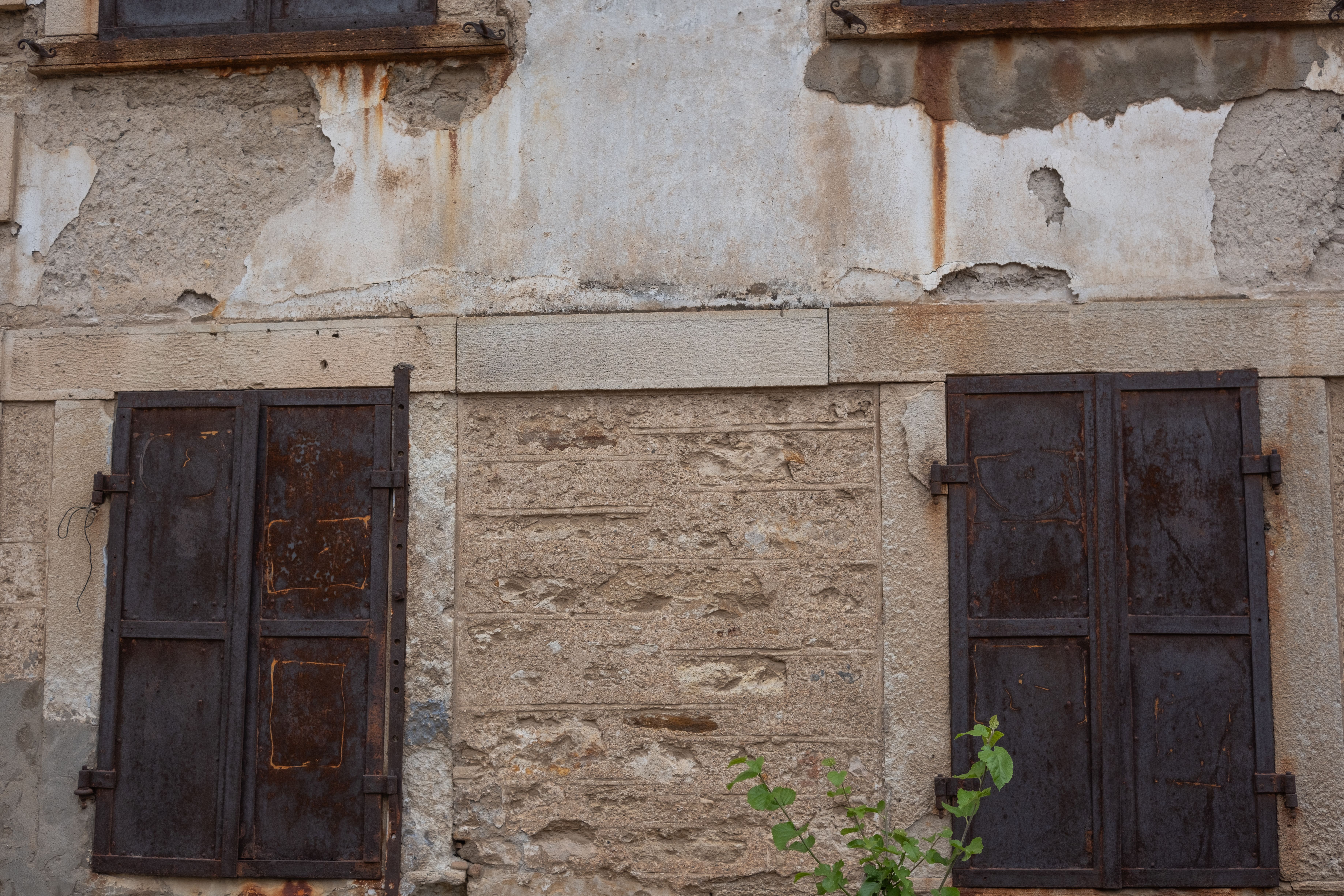 Rustic stone wall with aged wooden shutters in Foça, İzmir, showcasing urban decay. - Izmir