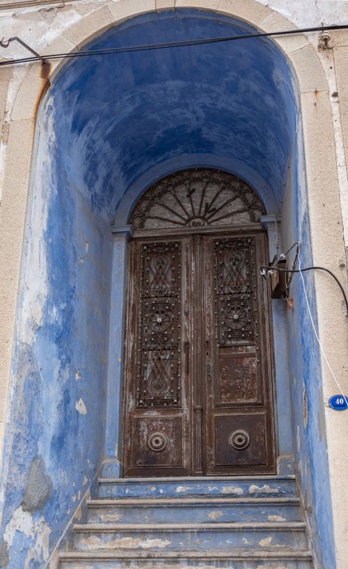Free A beautifully aged wooden door within a blue archway in Foça, İzmir, Türkiye. Stock Photo